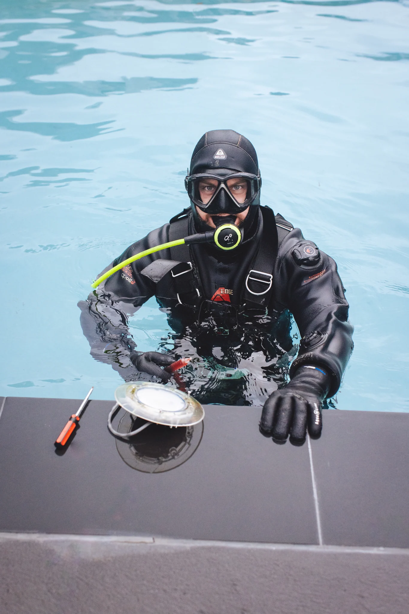 Pool leak detection diver inspecting a swimming pool with specialist equipment